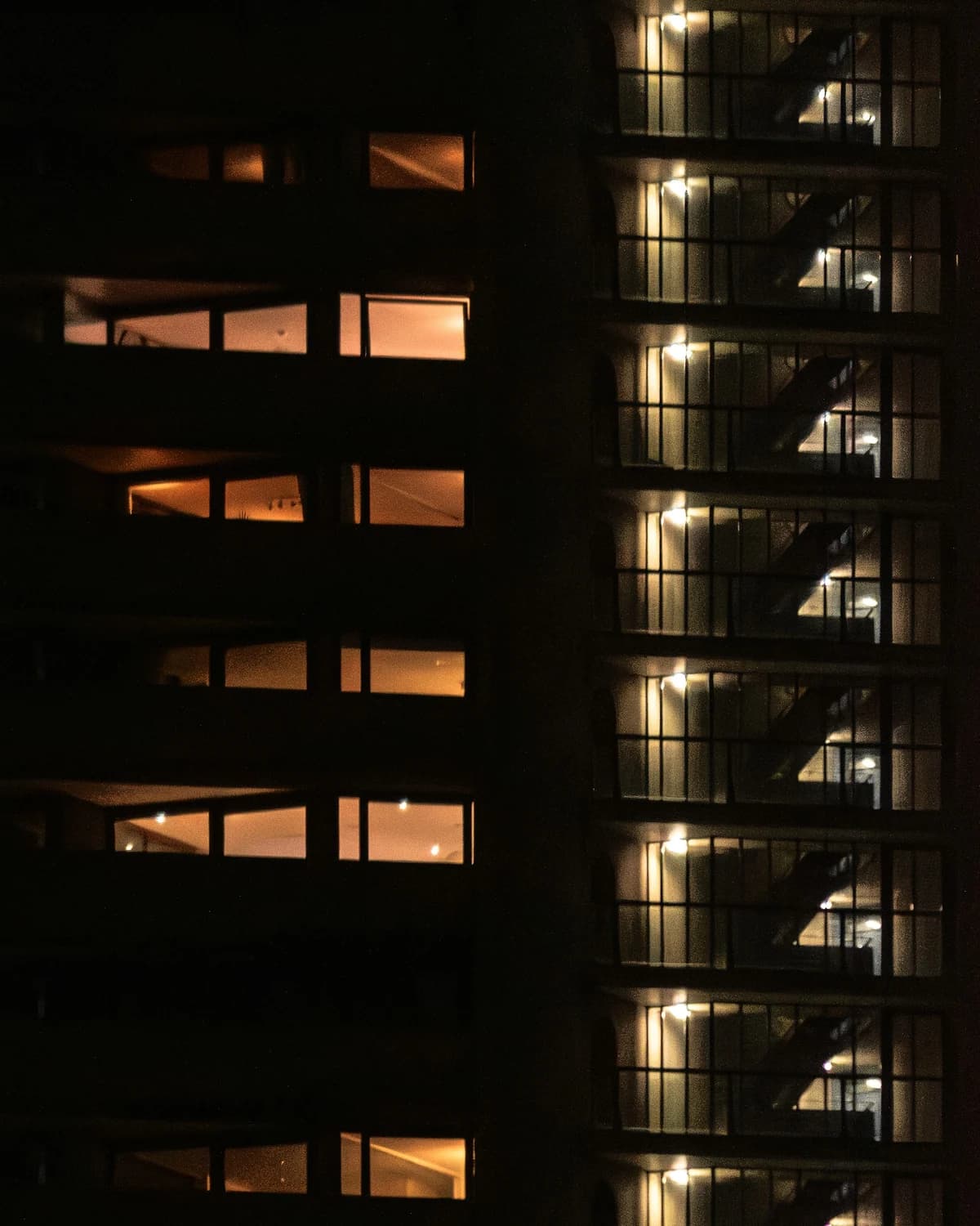 Lit balconies stacked up a residential tower at night.