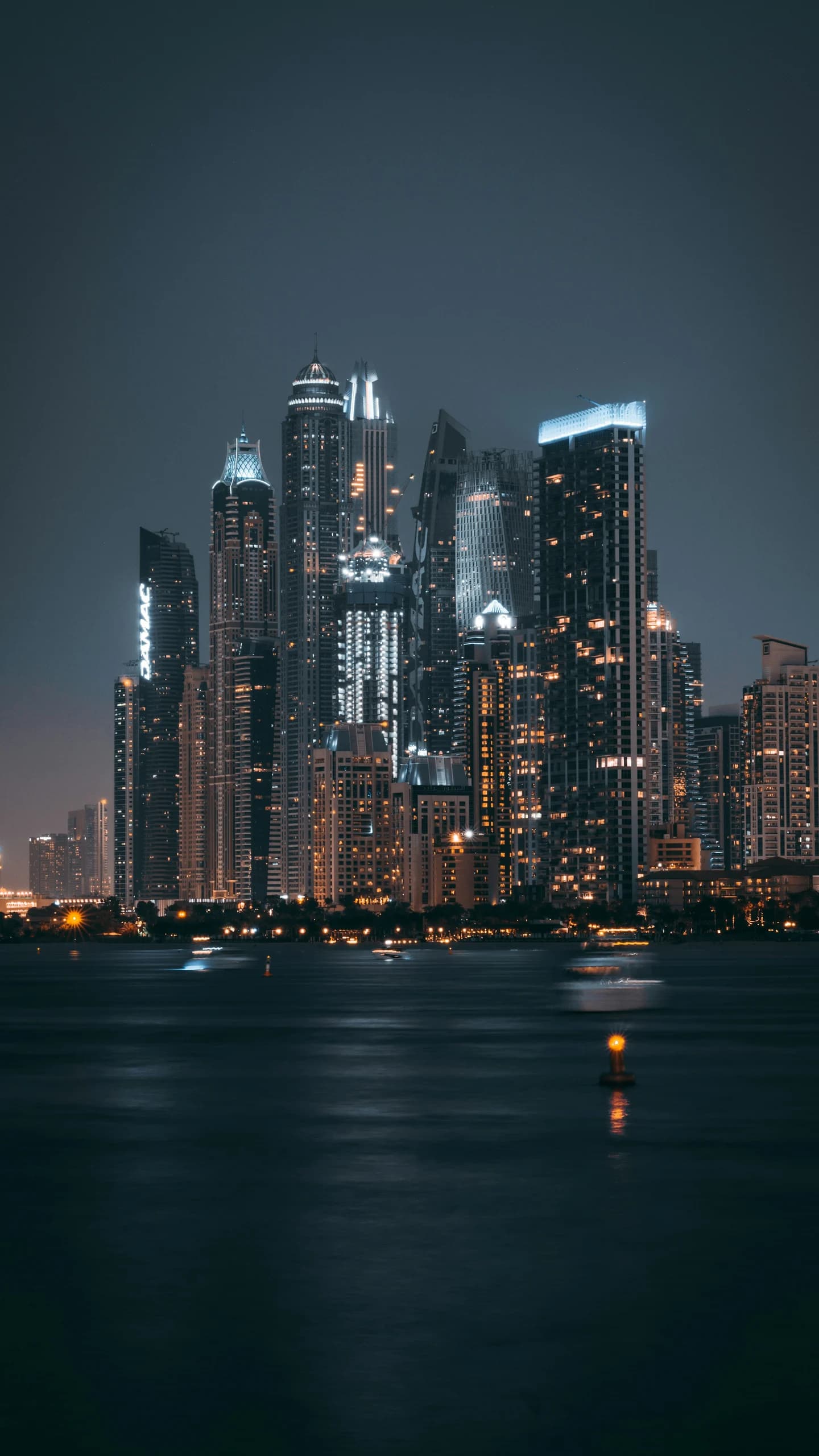 Dubai Marina towers lit at blue hour above the water.